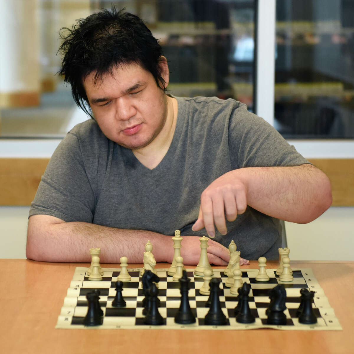 Glenville resident Zachary Tanenbaum, 22, moves a chess piece at Greenwich Library in Greenwich, Conn. Monday, Dec. 5, 2022. Tanenbaum, a graduate of Greenwich High School, is an acclaimed chess player and recently won the Connecticut State Chess Association 2022 Player of the Year award.