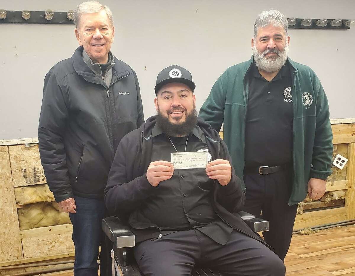 From left, in back, Corporation for New Milford Economic Development Chairman Oley Carpp, left, and New Milford Mayor Pete Bass, right, congratulate Christopher Derby of New Milford for the Facade Improvement Grant he received to improve his future barber shop at 56 Railroad St.