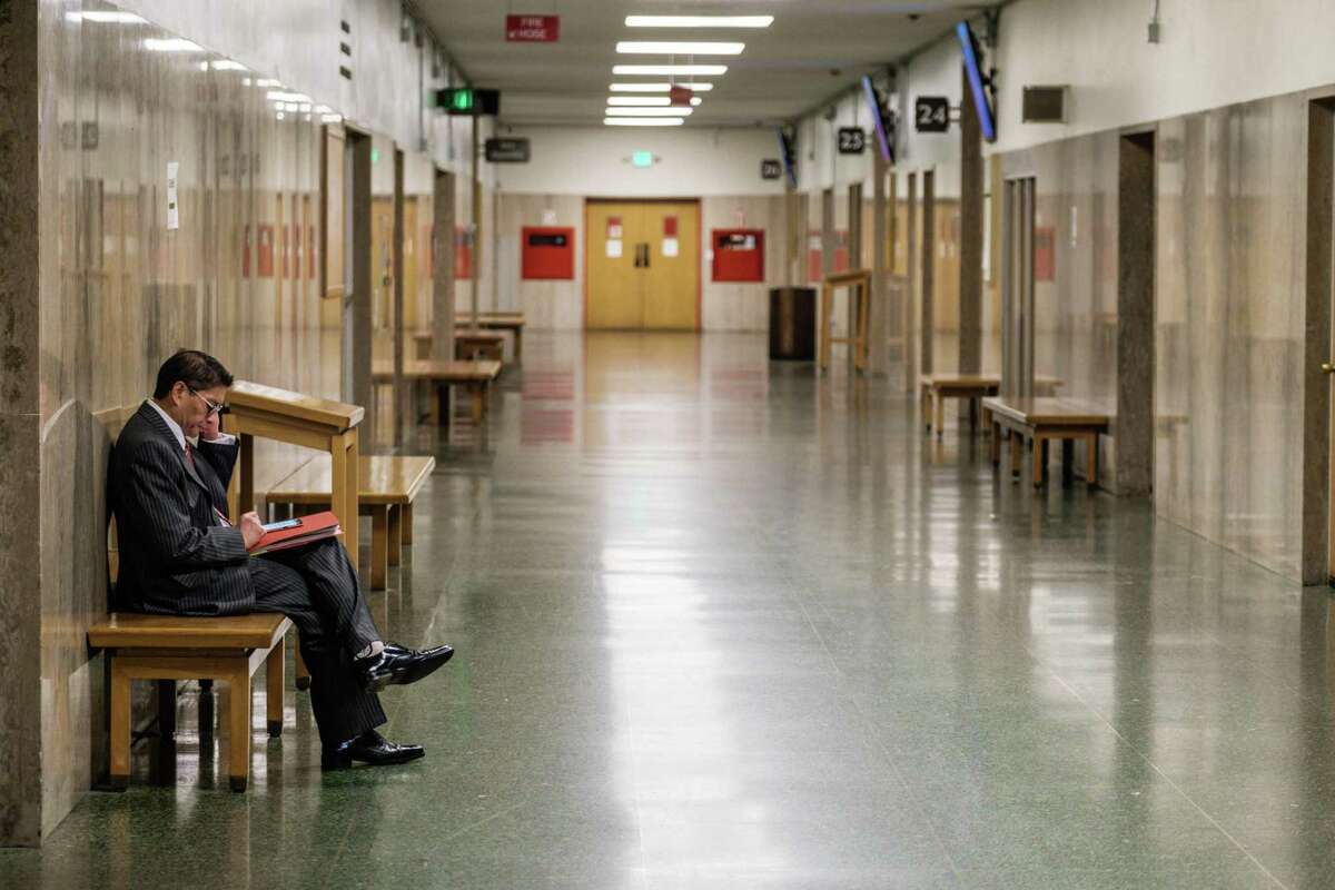 Attorney Conrad Del Rosario sits in an empty hallway at S.F. Superior Court. California courts have seen a drastic decline in filings, Chief Justice Tani Cantil-Sakauye said.