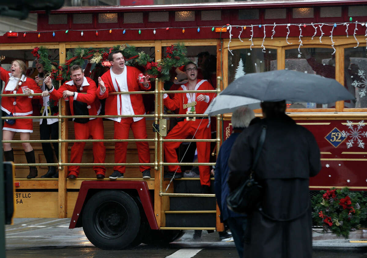 SantaCon participants whoop it up aboard a motorized cable car circling Union Square for the annual SantaCon romp in San Francisco, Calif. on Saturday, Dec. 10, 2016. 