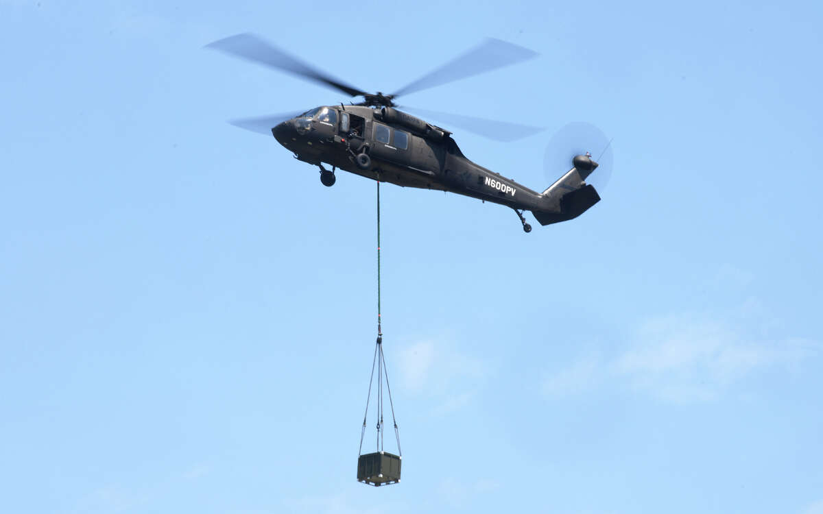 A Sikorsky UH-60A Black Hawk helicopter hovers with a payload at Sikorsky Memorial Airport, in Stratford, Conn. July 13, 2022. Sikorsky uses the helicopter for test flights for a new Aircrew Labor In-Cockpit Automation System (ALIAS), a fly-by-wire system that will allow it to be flown with no people aboard.
