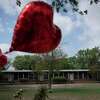 A heart-shaped balloon flies decorating a memorial site outside Robb Elementary School in Uvalde, Texas, Monday, May 30, 2022. Nineteen children and two teachers were killed by an 18-year-old gunman at the school last week. (AP Photo/Wong Maye-E)