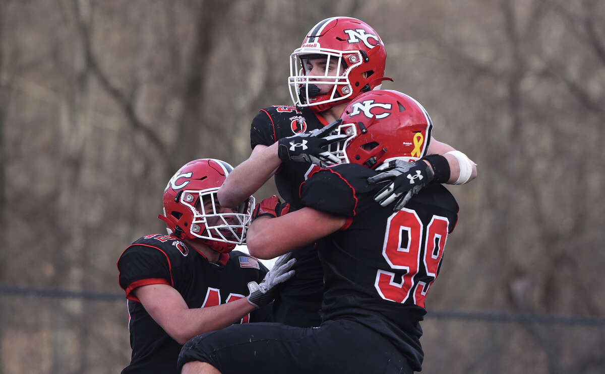 New Canaan's Luke Reed (25), Will Pepe (99) and Thomas Garcia (42) celebrate a touchdown against Cheshire during the CIAC Class L football semifinals at Dunning Field on Sunday, Dec. 4, 2022.