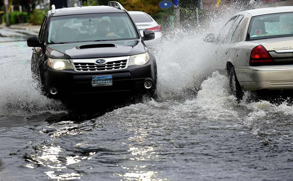 FILE PHOTO: Cars drive through flooding on Water Street in 2021. South Norwalk was selected among seven neighborhoods in Fairfield and New Haven counties for a state program developing climate mitigation plans.