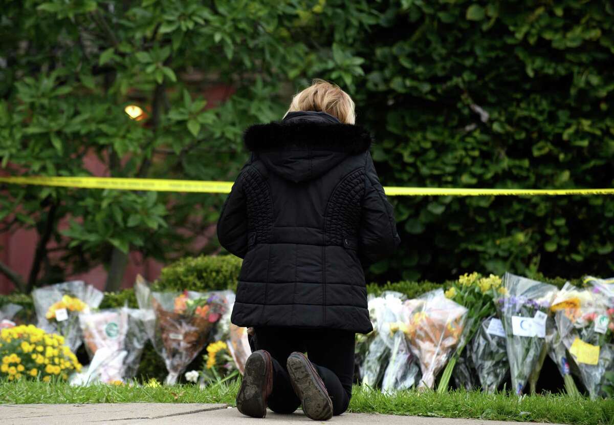 A woman prays after laying flowers outside the Tree Of Life Synagogue following the mass shooting there in 2018. Antisemitic incidents have been on the rise, and we serve no one by ignoring this.