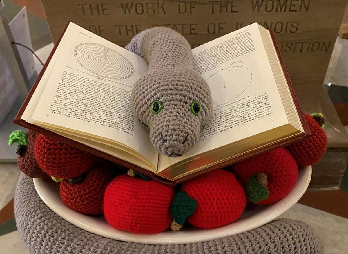 The Satanic Temple of Illinois' 2022 holiday display is pictured on the Illinois Capitol rotunda. It consists of a crocheted snake sitting on a book and a pile of apples crocheted by Temple members.  