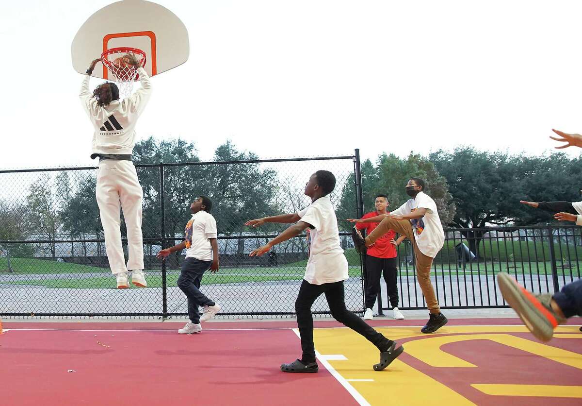 Houston Rockets guard Jalen Green dunks the ball as students with The Urban Enrichment Institute warm up on the newly updated basketball court he and Adidas contributed to at Brewster Park in Fifth Ward on Tuesday, Dec. 6, 2022 in Houston.The court was updated with new LED lights, baskets and artwork reflecting Houston’s culture and symbols important to Green.