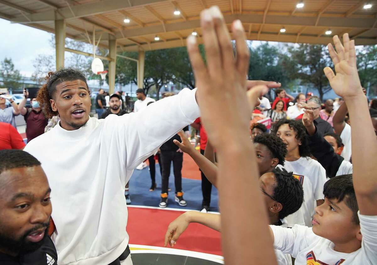 Houston Rockets guard Jalen Green picks out students to play a round of knockout with after unveiling a newly updated basketball court at Brewster Park in Fifth Ward on Tuesday, Dec. 6, 2022 in Houston.The court was updated with new LED lights, baskets and artwork reflecting Houston’s culture and symbols important to Green.