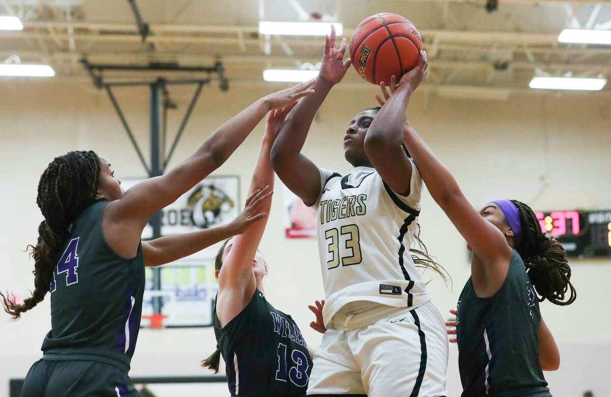 Conroe's Nevaeh Small (33) is fouled by Willis' Essence Traylor (2) beside Willis' Anastacha Mcgowen (14) and Wienecke (13) during the first quarter of a District 13-6A high school basketball game at Conroe High School, Tuesday, Dec. 6, 2022, in Conroe.