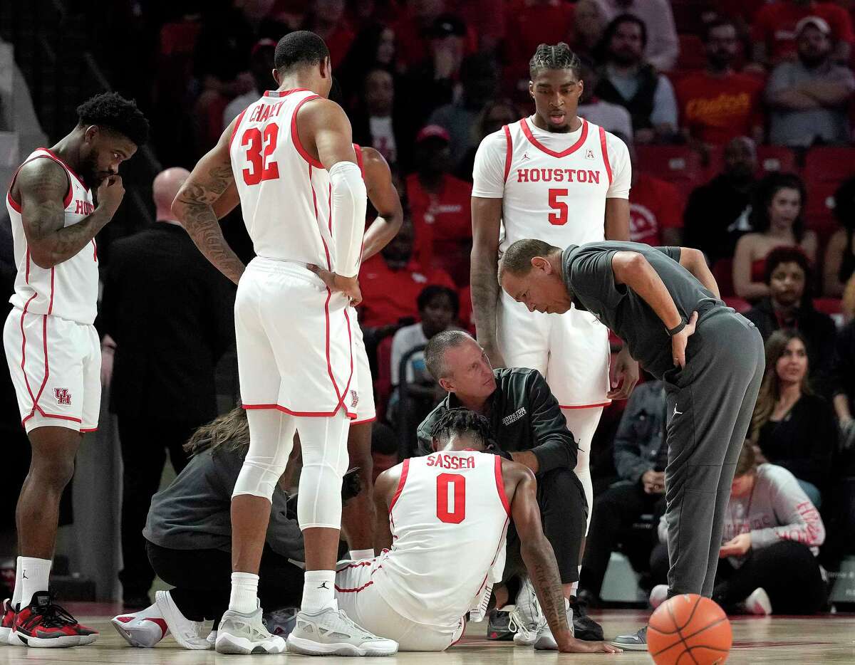 Houston Cougars head coach Kelvin Sampson checks on guard Marcus Sasser (0) after he sustained an injury to his face during the first half of an NCAA men’s basketball game at the Fertitta Center on Tuesday, Dec. 6, 2022 in Houston .