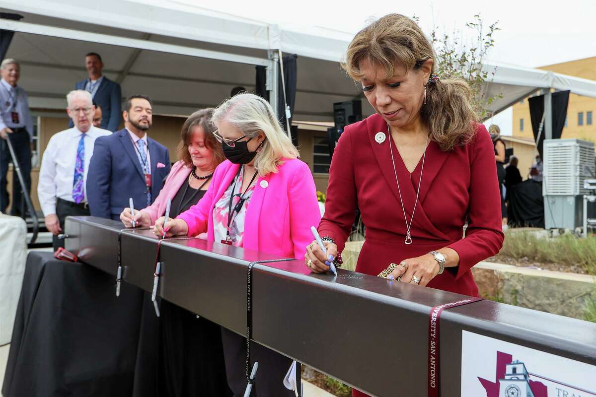 Texas A&M University-San Antonio President Cynthia Teniente-Matson, right, signs her name on a beam during a ceremony for the new College of Business & Library Hall at the school in 2021.