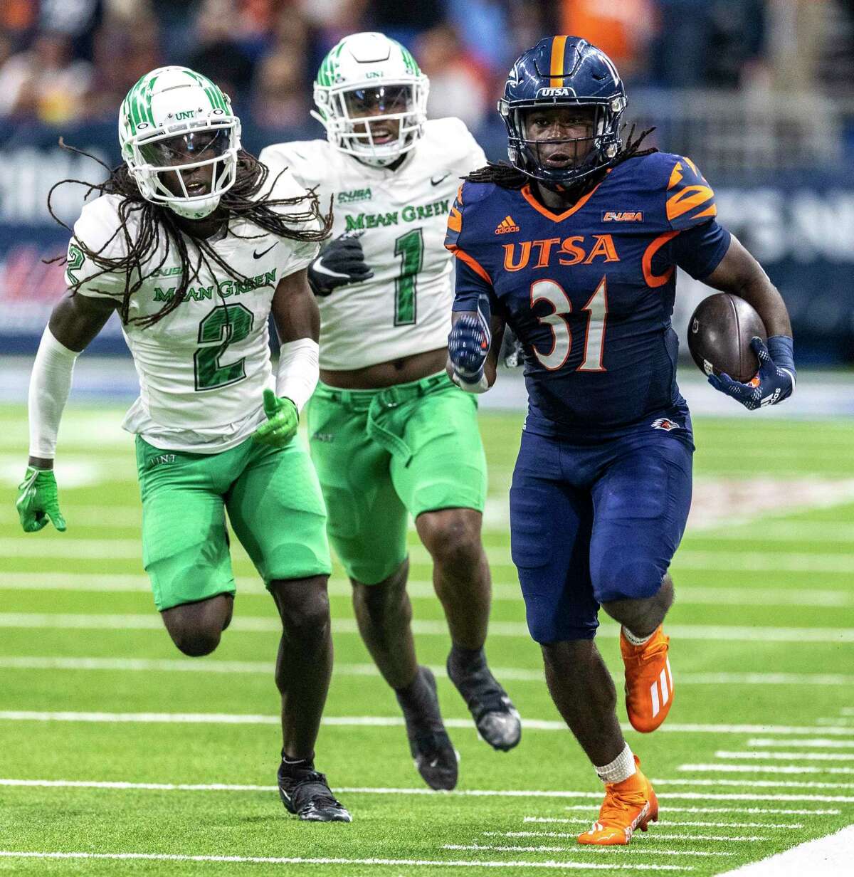 UTSA Roadrunners running back Kevorian Barnes (31) rushes the sideline Friday night, Dec. 2, 2022 at the Alamodome while North Texas Mean Green quarterback Austin Aune (2) and North Texas Mean Green linebacker KD Davis (1) try to chase him down during the C-USA championship game.
