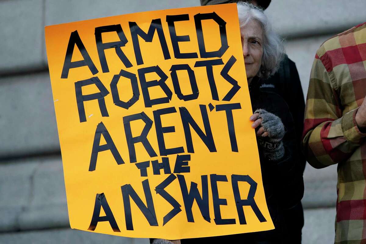 FILE - Diana Scott holds up a sign while taking part in a demonstration about the use of robots by the San Francisco Police Department outside of City Hall in San Francisco, Monday, Dec. 5, 2022. San Francisco supervisors have voted put the brakes on a controversial policy that would let police use robots for deadly force. The Board of Supervisors voted Tuesday to send the issue back to a committee for further discussion. (AP Photo/Jeff Chiu, File)