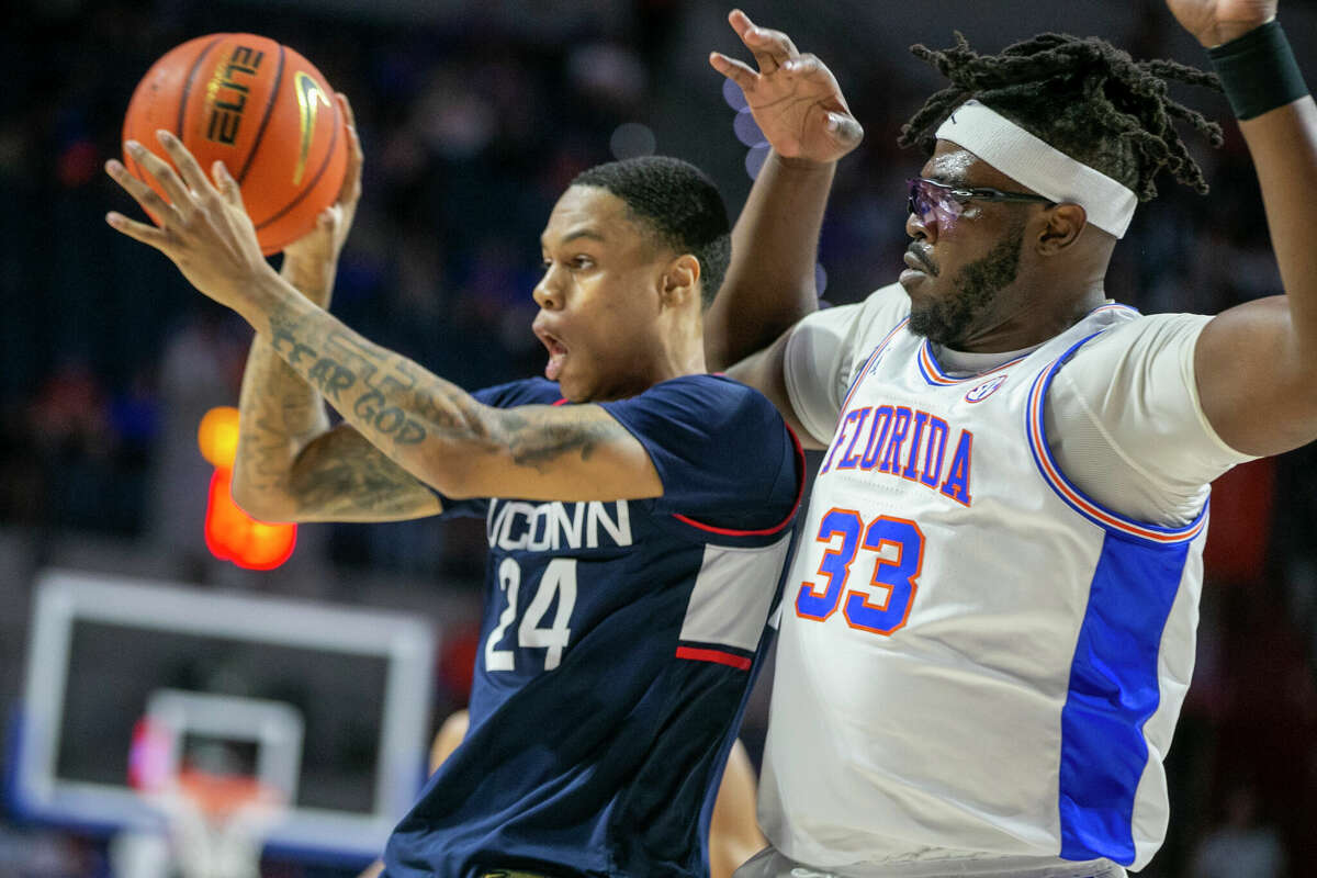 Connecticut guard Jordan Hawkins (24) is defended by Florida center Jason Jitoboh (33) during the first half of an NCAA college basketball game Wednesday, Dec. 7, 2022, in Gainesville, Fla. (AP Photo/Alan Youngblood)
