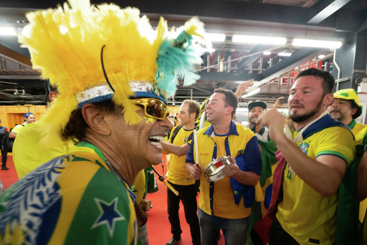 Brazilian Wallace Leite (left) smiles while playing his drum while leading some fans in a chant after the Brazil and South Korea World Cup game at Stadium 974 in Doha, Qatar on December 5, 2022.