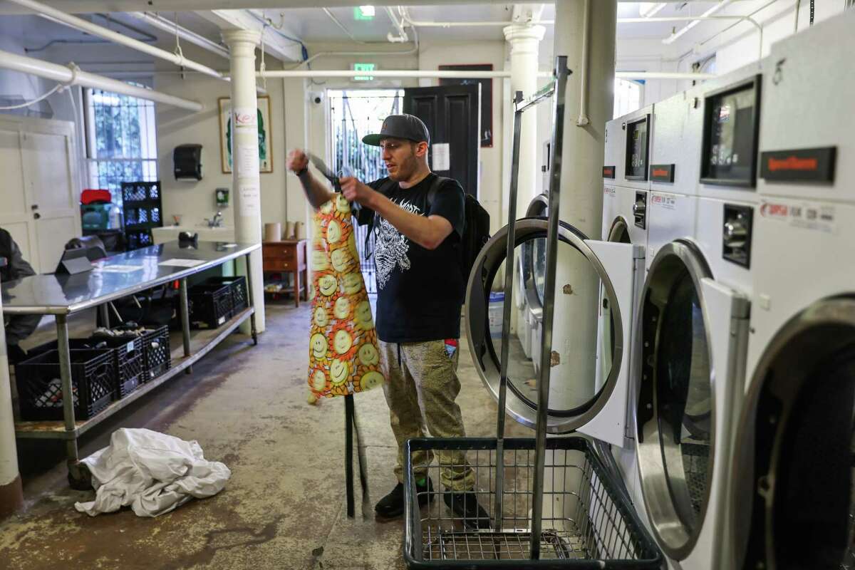 Ben Campofreda, a recovering fentanyl addict, organizes a piece of laundry at his drug rehabilitation program at Walden House where hopeful messages are on the walls in San Francisco, Calif., on Saturday, Nov. 6, 2022. He is recovering from multiple surgeries while getting drug treatment.