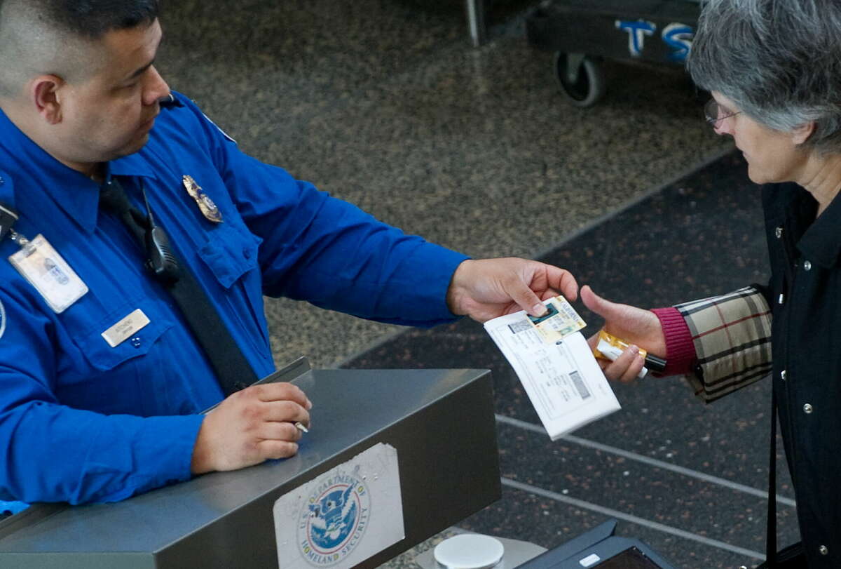 A TSA agent checks the identification of a passenger passing through security in the terminal at Ronald Reagan Washington National Airport in Arlington, Va.