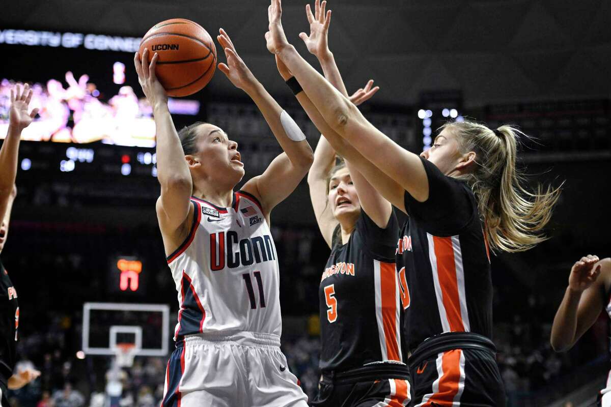 Connecticut's Lou Lopez-Senechal, left, shoots as Princeton's Paige Morton, center, and Ellie Mitchell defend during the first half of an NCAA college basketball game Thursday, Dec. 8, 2022, in Storrs, Conn.