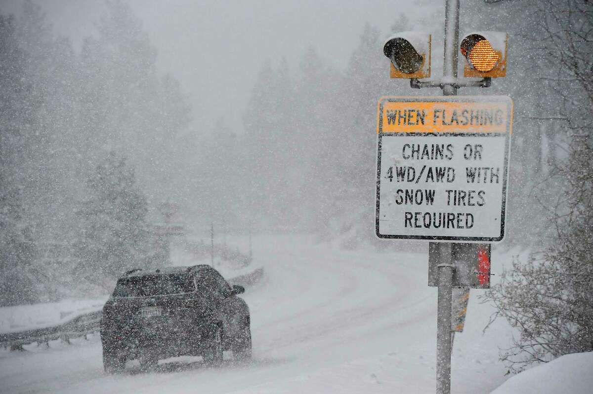 California winter storm makes Tahoe travel difficult to impossible. A car passes a caution sign as heavy snow falls on the Mt. Rose Highway near Reno, Nev.