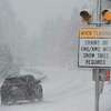 A car passes a caution sign as heavy snow falls on the Mt. Rose Highway near Reno, Nev.