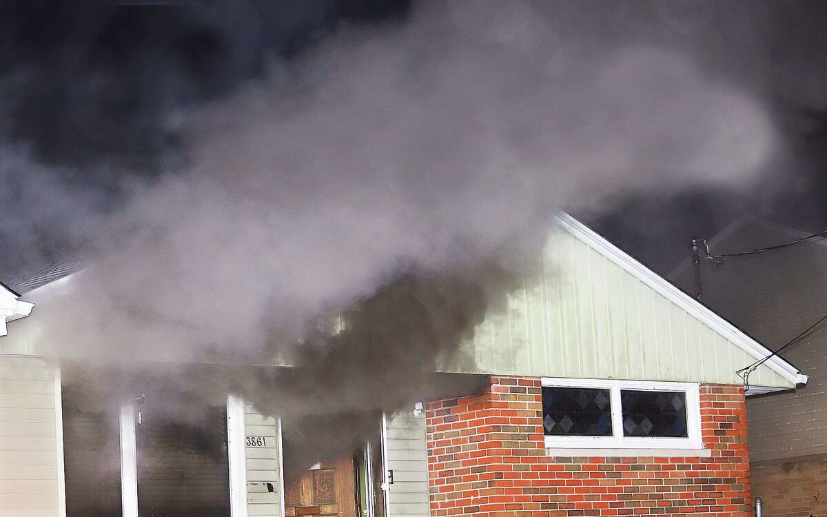 Johm Badman|The Telegraph Smoke billows from the open front door as firefighters arrived to find the house had caught fire late Thursday night in the 3800 block of Horn Street in Alton. 