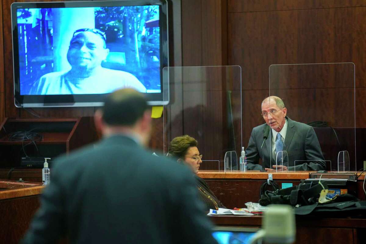 Randy Croft testifies with a photo of Michael Haney over his shoulder during the murder trial against Lance Campbell in Houston on Friday, December 9, 2022.  Campbell, 30, is on trial in the 174th District Court on murder charges related to the June 2019 shooting of homeless man Haney, 60, outside Washateria near Hobby Airport.