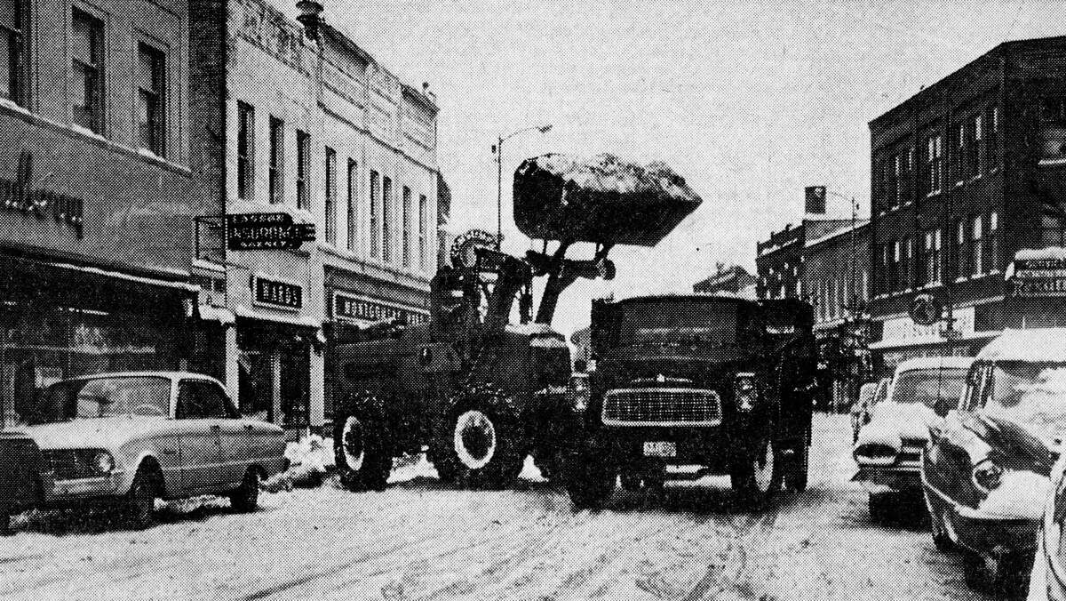 With the large amount of snow which has fallen in the past three days, snow removal problems are increasing and city motorists would help matters by obeying, "No Parking" signs on River Street when posted on parking meters so that snow removal equipment can continue working without waiting for parked cars. The photo was published in the News Advocate on Dec. 11, 1962.