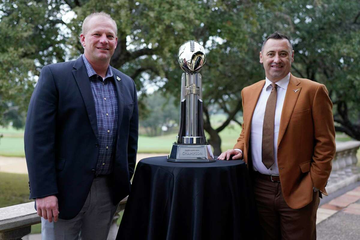 Washington head coach Kalen DeBoer, left, and Texas head coach Steve Sarkisian, right, pose with the Alamo Bowl trophy before a news conference for the Alamo Bowl NCAA college football game, Thursday, Dec. 8, 2022, in San Antonio. The teams will play in this year's Alamo Bowl. (AP Photo/Eric Gay)