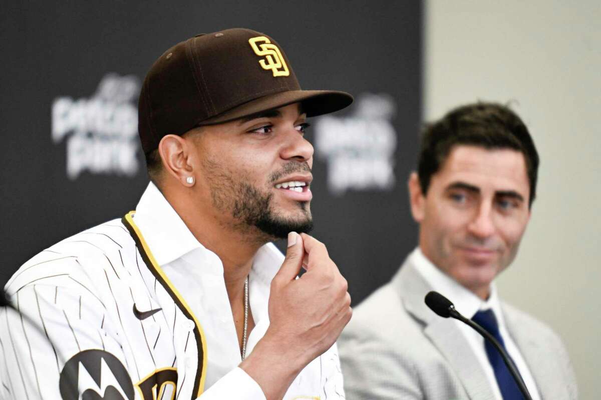 San Diego Padres' Xander Bogaerts, left, plays with his beard as general manager A.J. Preller looks on at a news conference held to announce that Bogaerts' $280 million, 11-year contact with the Padres has been finalized, Friday, Dec. 9, 2022, in San Diego. (AP Photo/Denis Poroy)
