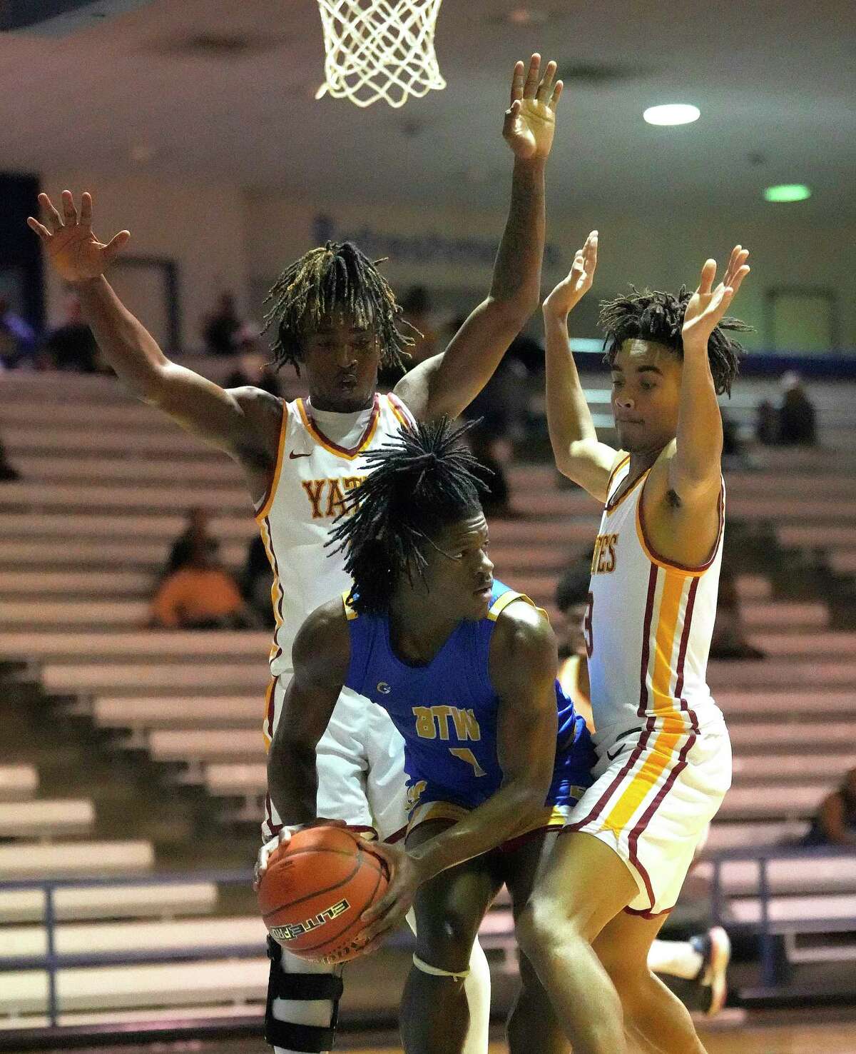 Washington’s Andre Walker (1) looks to pass the ball between Yates Broderick Brown (1) and Calvin Murphy (3) during the second half of a high school District 21-4A boys basketball game at Barnett Fieldhouse on Friday, Dec. 9, 2022 in Houston. Washington beat Yates 101-49.