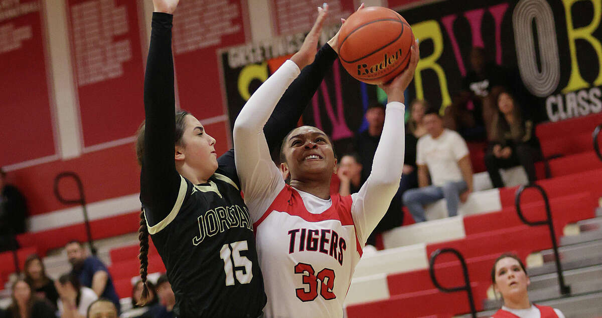 Katy Tigers Lyric Barr (30) drives to the basket on Jordan Warriors Allie Hakinzadeh (15) during a District 19-6A girls basketball game between Jordan and Katy December 9, 2022 in Katy,Texas.