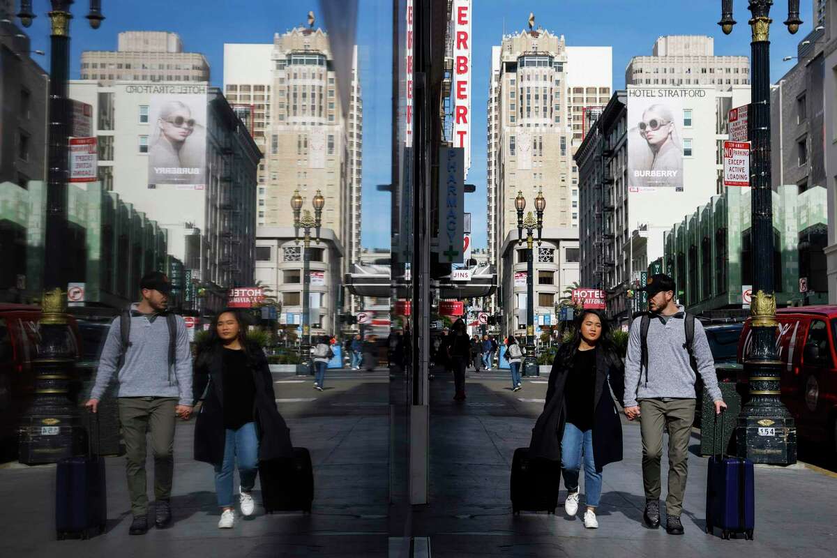 Pedestrians walk past empty storefronts along Powell Street at Union Square in San Francisco in 2022.