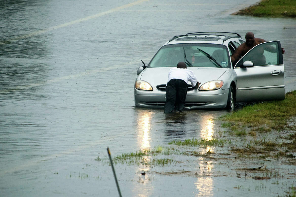 HOUSTON, TX - SEPTEMBER 14: Motorists push a vehicle from high water during early morning rains in the wake of Hurricane Ike September 14, 2008 in Houston, Texas. Floodwaters from Hurricane Ike are reportedly as high as eight feet in some areas causing widespread damage across the coast of Texas. (Photo by Smiley N. Pool-Pool/Getty Images)