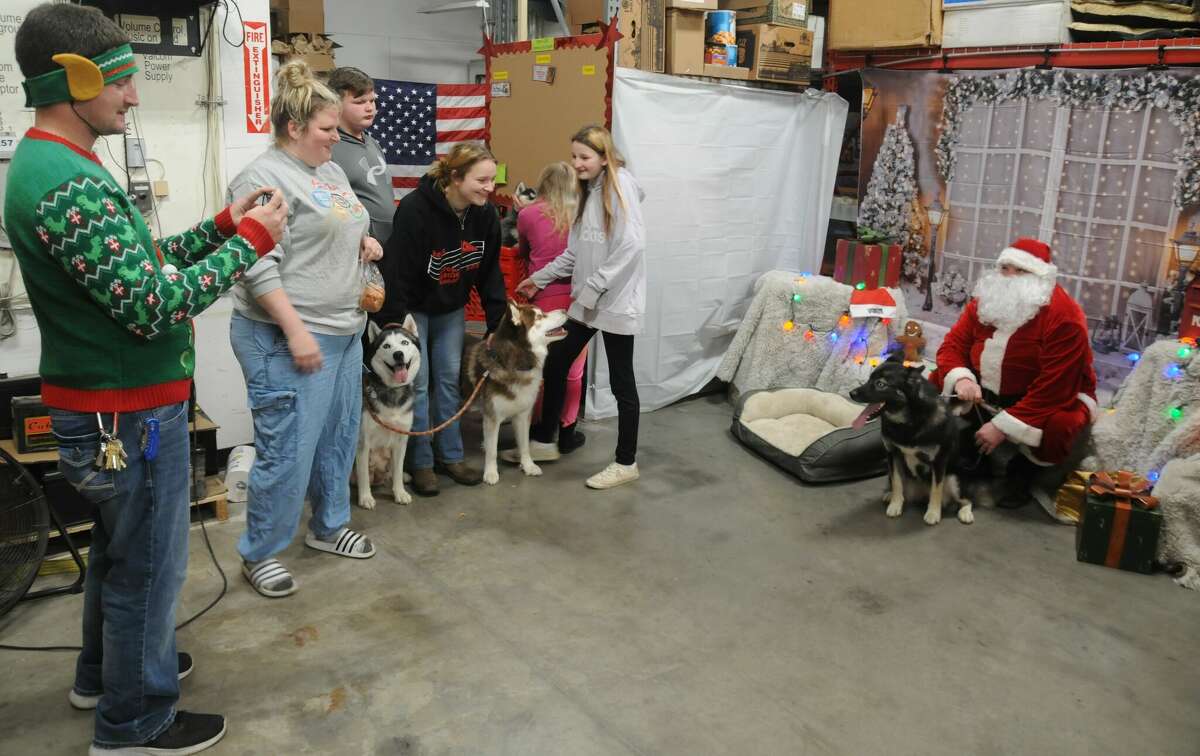 Tiffany Yinder and her family wait as the first of their many dogs gets a photo with St. Nick during the Pet Santa event on Saturday at the Alton TSC store.