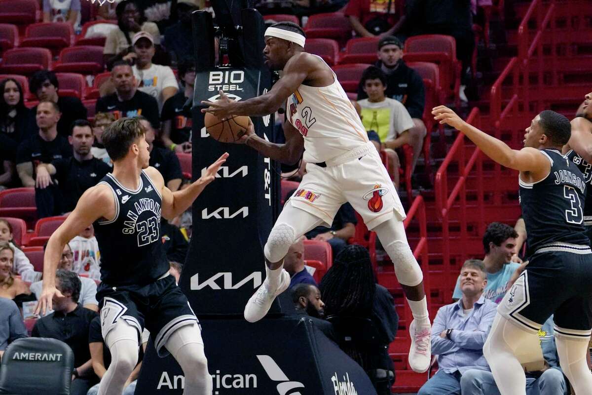 Miami Heat forward Jimmy Butler (22) looks to pass the ball as San Antonio Spurs forward Zach Collins (23) and forward Keldon Johnson (3) defend during the first half of an NBA basketball game Saturday, Dec. 10, 2022, in Miami.
