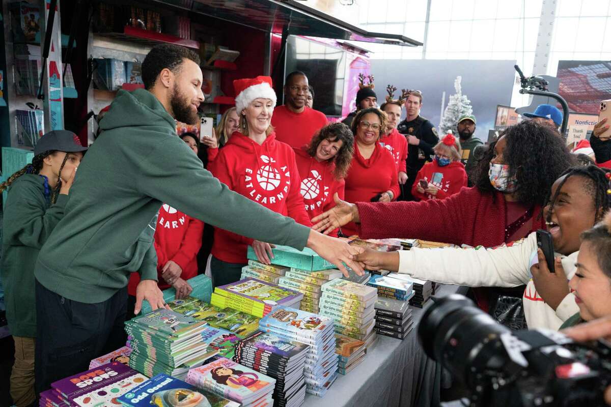Steph Curry, left, greets a young fan during the Christmas with the Currys event at the Bridge Yard in Oakland, California on Sunday, December 11, 2022. The “Winter Wonderland” themed gathering distributed gifts to over 500 Oakland families, as part of the Curry’s Eat Learn Play organization.