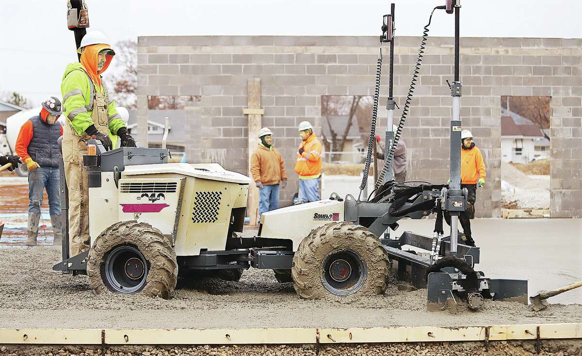 John Badman|The Telegraph An operator uses a machine to drive through and level the concrete poured Monday for the new Wood River Recreation Center.