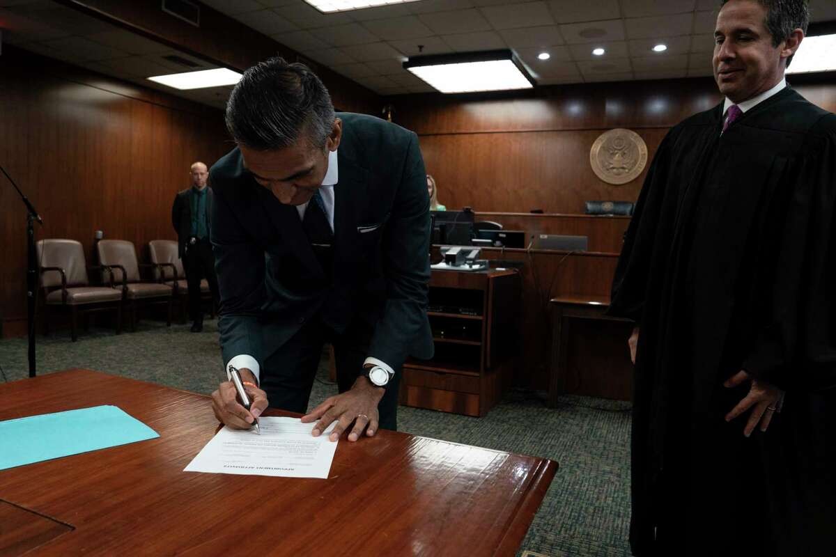 Alamdar Hamdani signs the appointment affidavit after being sworn in as U.S. Attorney for the Southern District of Texas by in McAllen, Monday, Dec. 12, 2022.
