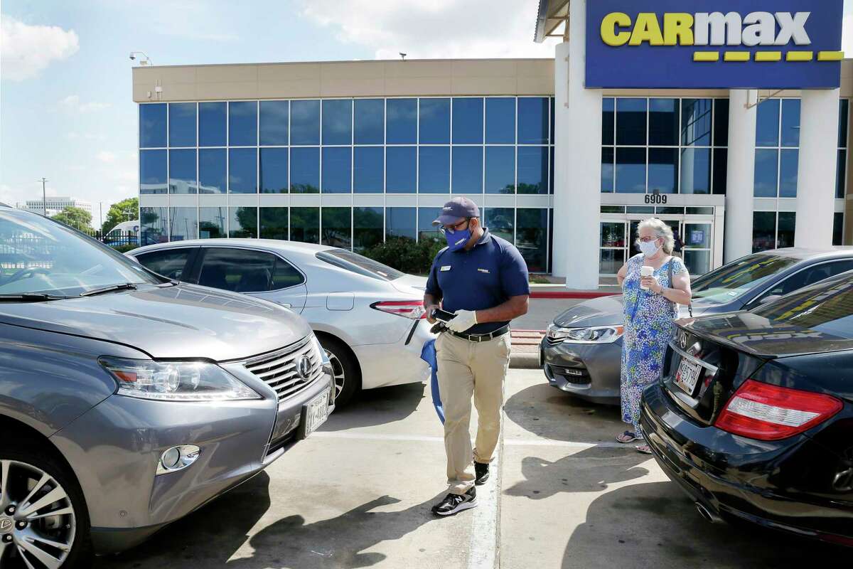 CarMax has agreed to pay $1 million as part of an agreed settlement with attorney generals from Texas and 35 other states over the company’s alleged failure to disclose safety recalls. In 2020 in Houston, CarMax buyer Bobby Sheik, left, looks over a Lexus SUV brought in by the owner, right, for a possible sale.