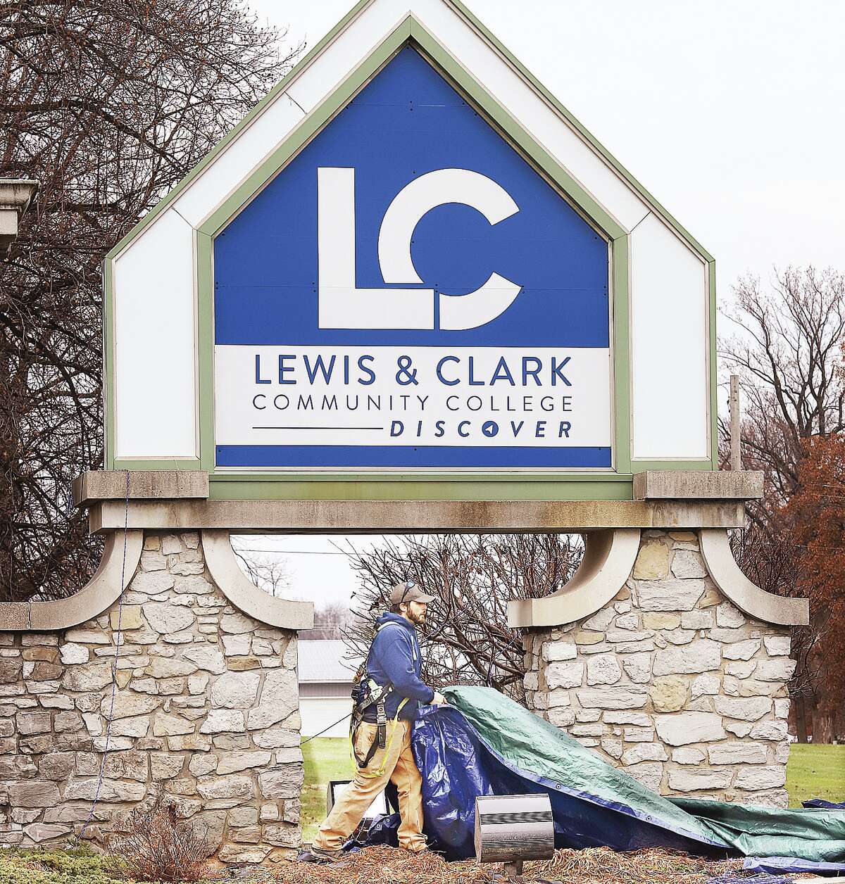 John Badman|The Telegraph A worker at Lewis and Clark Community College in Godfrey pulls the tarp off the college's new logo Monday afternoon. The college held an event Monday launching efforts to re-brand the institution which included a new sans serif logo typestyle.