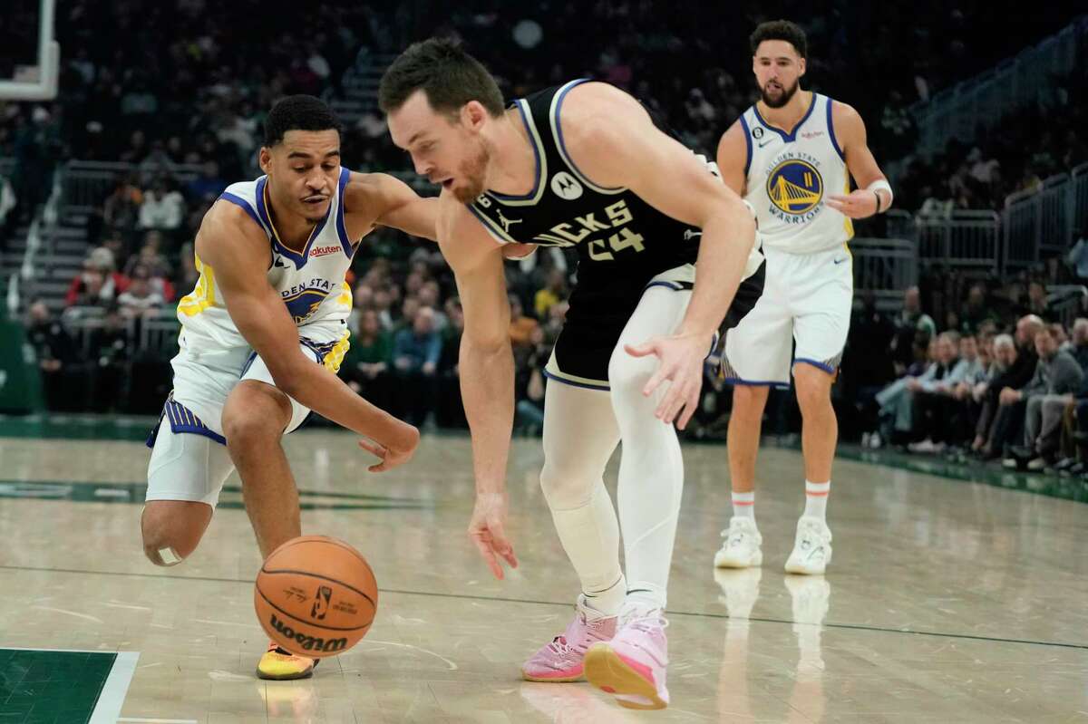 Milwaukee Bucks' Pat Connaughton and Golden State Warriors' Jordan Poole go after a loose ball during the first half of an NBA basketball game Tuesday, Dec. 13, 2022, in Milwaukee. (AP Photo/Morry Gash)