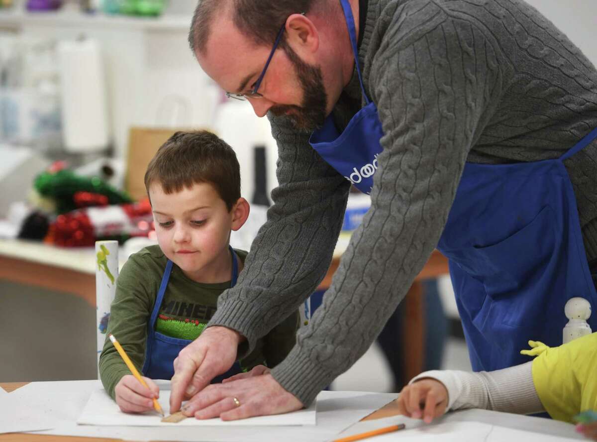 Student artist Beckett Moyer, 6, uses a ruler to draw his horizon line with the help of Walter Chistoni, of Trumbull, during a youth art class on perspective painting on canvas at the new Abrakadoodle art studio at 2285 Reservoir Avenue in Trumbull, Conn. on Tuesday, December 13, 2022.