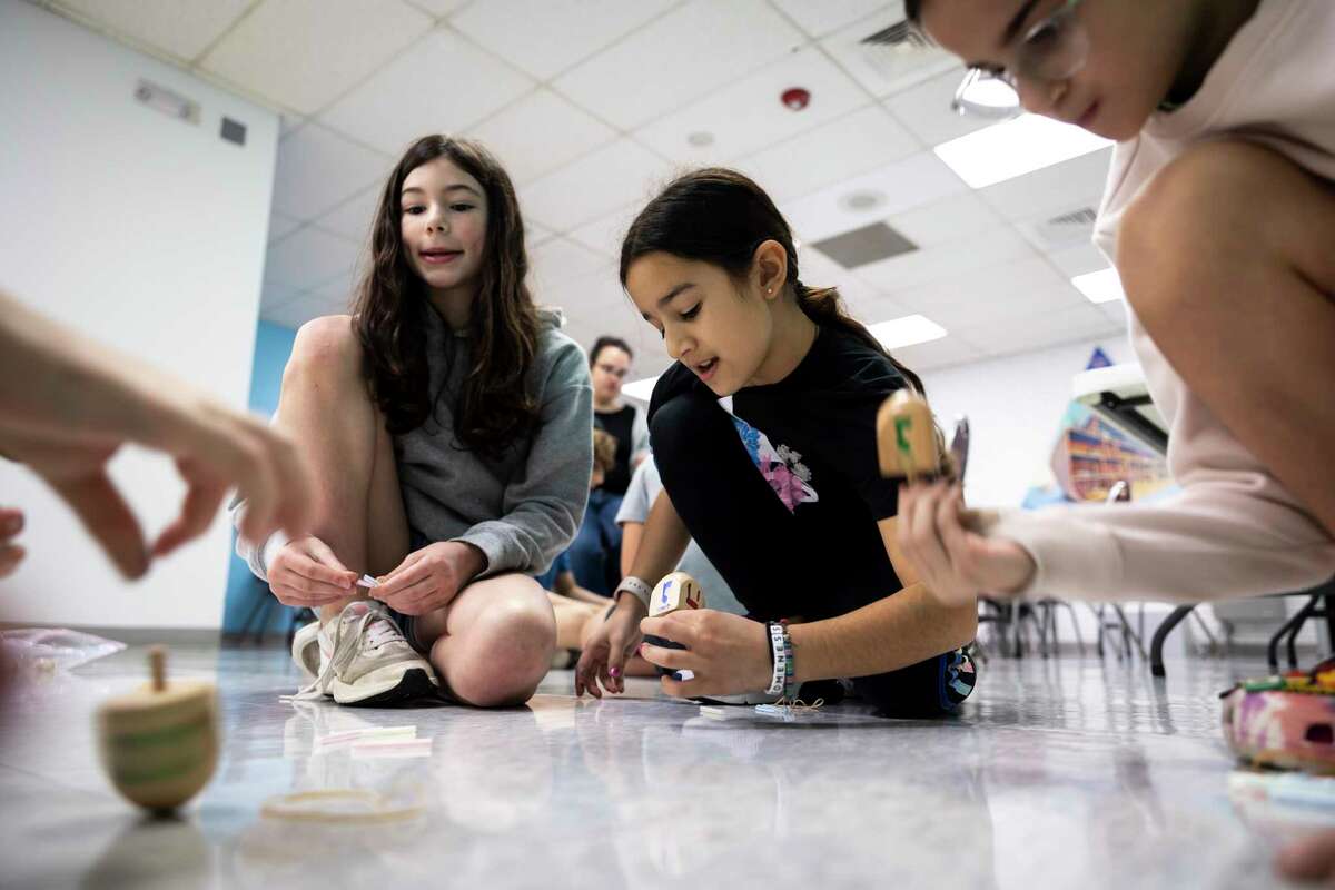 Emma Churchill, left, and Lexi Cohen join a small group of friends to play dreidel during classes for religious school students at Congregation Beth Yeshurun on Sunday, Dec. 11, 2022. Students learn all about Hanukkah, play dreidel and participate in crafts and other games.
