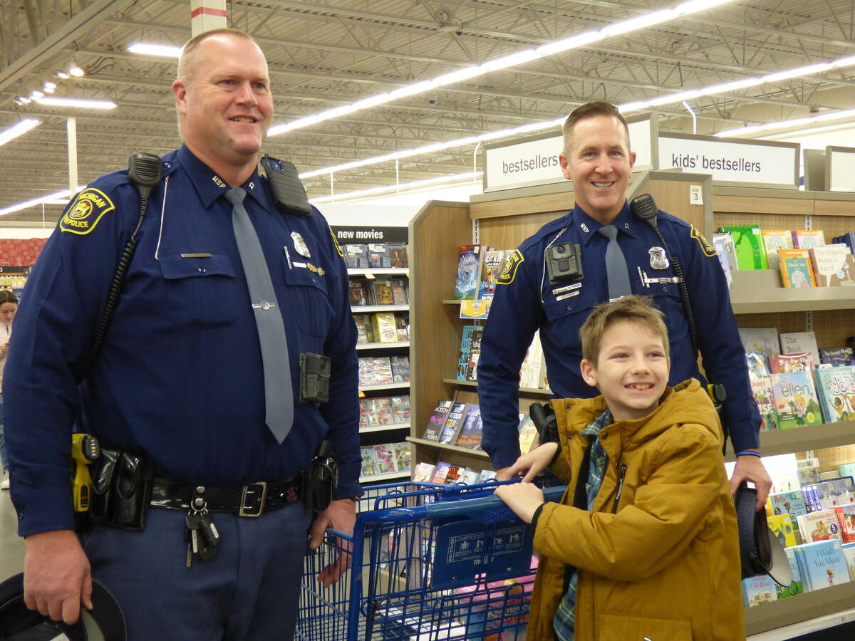 Michigan State Police troopers David Skorka (left) and Mike Korzek help at the Shop with a Hometown Hero event on Dec. 14 in Manistee. 