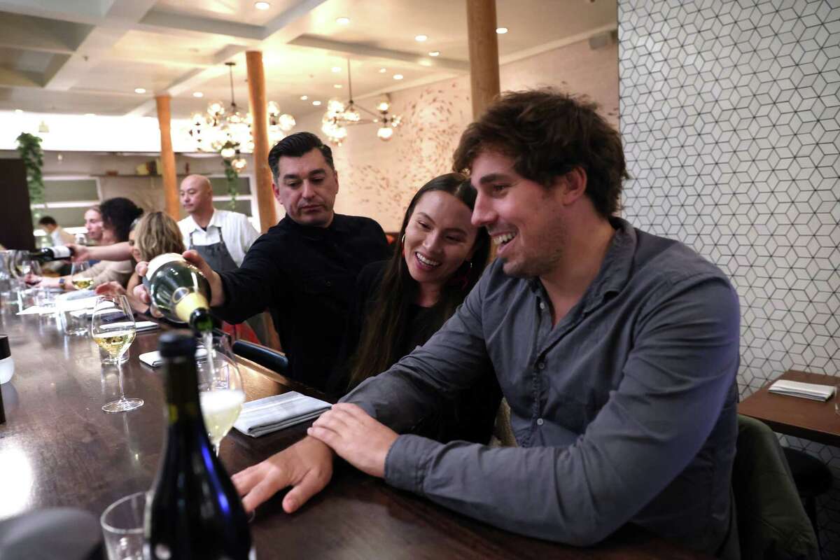 Daniel Urrutia pours sparkling wine for diners Meg Mansfield and Alex Araiz at Ancora in San Francisco on Dec. 7.