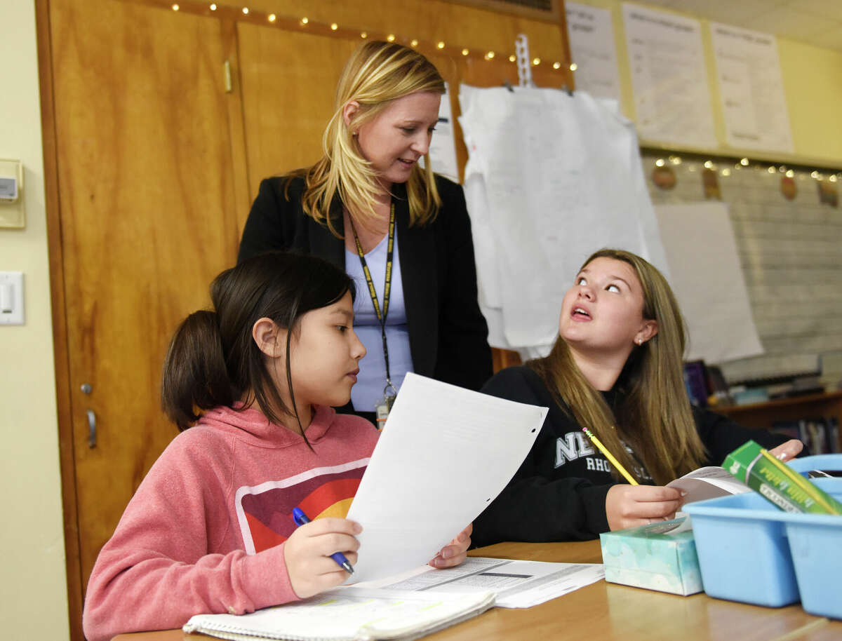 Assistant Principal Suzanne Coyne checks in with eighth graders Amelia Ilker, left, and Kylie Douglass during class at Western Middle School in Greenwich, Conn. Thursday, Dec. 15, 2022. Coyne was recently named the Connecticut Association of Schools Middle School Assistant Principal of the Year.
