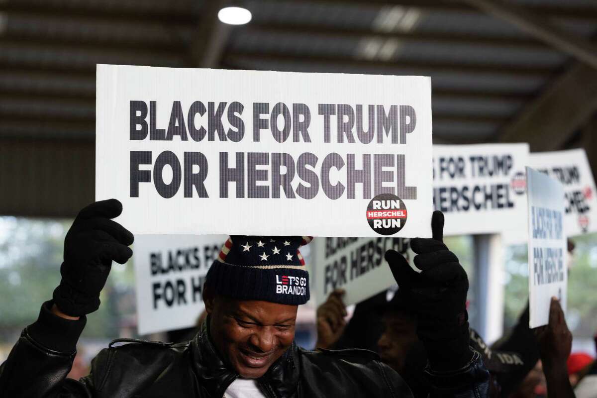 Members of 'Blacks for Trump' wave campaign signs during a rally for Republican Senate nominee Herschel Walker on November 21, 2022 in Milton, Georgia. 