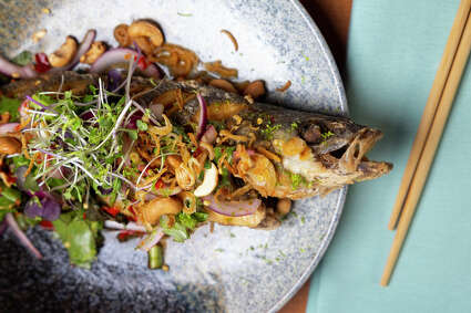 Whole, friend branzino fish topped with spicy mixed herb Thai salad at Street to Kitchen.