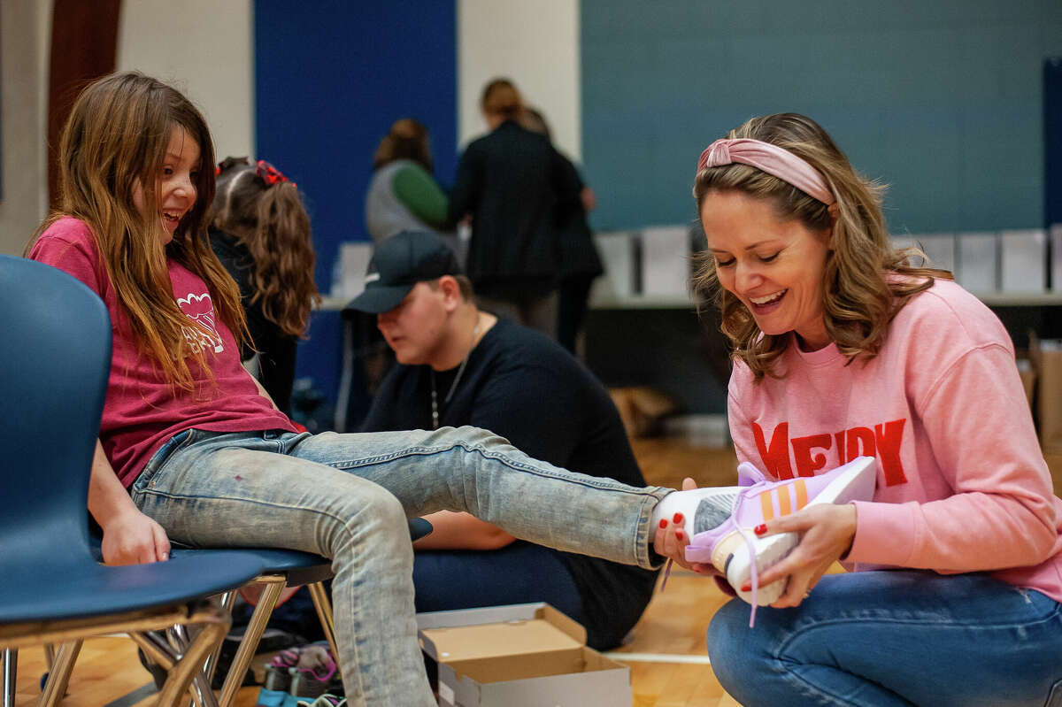Volunteer Rachel Acker puts a brand new pair of shoes on Meridian third-grader Mia Smalley on Dec. 15, 2022 at Meridian Elementary School. One Church in Sanford donated 560 pairs of shoes - a pair for every student at the school.