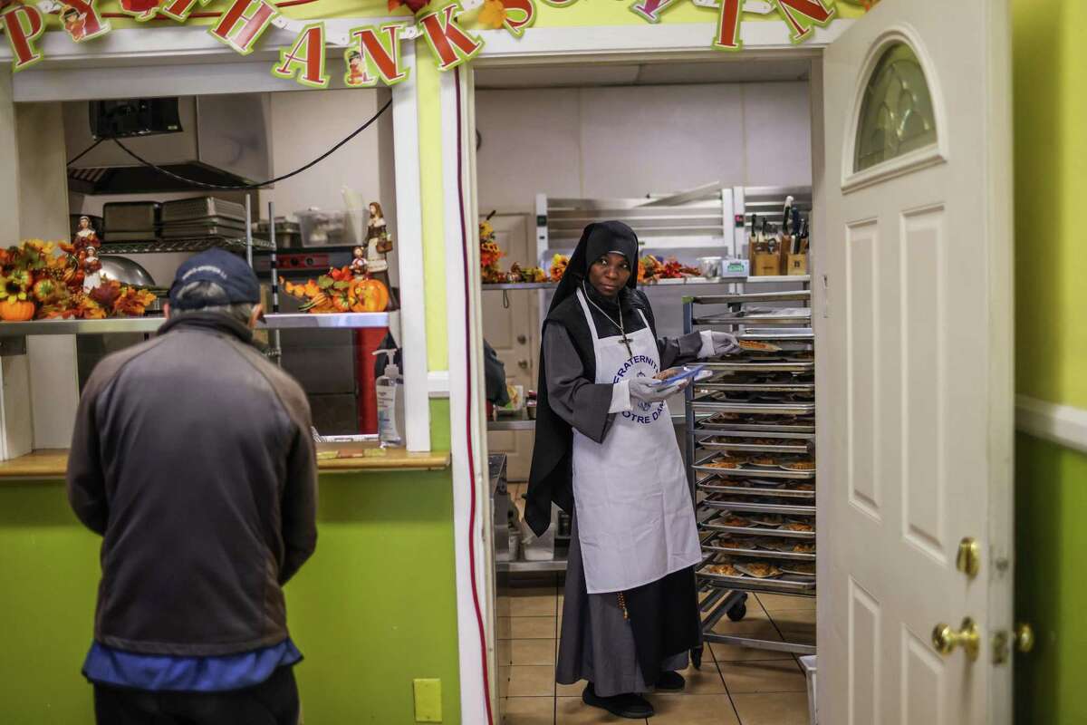 Sister Mary of the Rosary (right) looks out at the line as she helps prepare plates of food for people who are hungry at Fraternite Notre Dame’s Mary of Nazareth Soup Kitchen in the Tenderloin district of San Francisco, Calif., on Tuesday, Nov. 22, 2022.